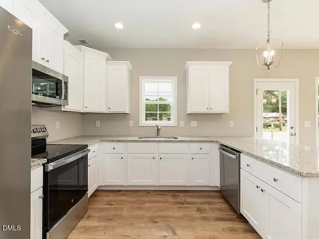 a large kitchen with stainless steel appliances granite countertop a stove a sink and a microwave