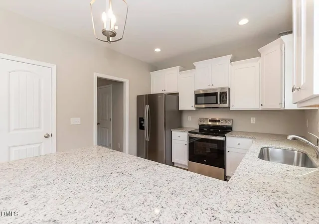 a kitchen with stainless steel appliances granite countertop a refrigerator a stove a sink and a microwave