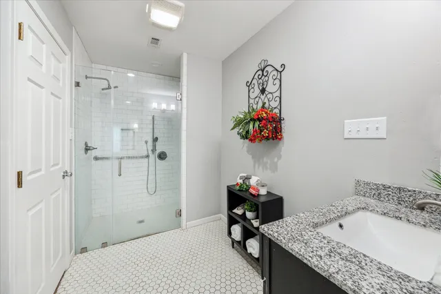 a bathroom with a granite countertop tub sink and mirror