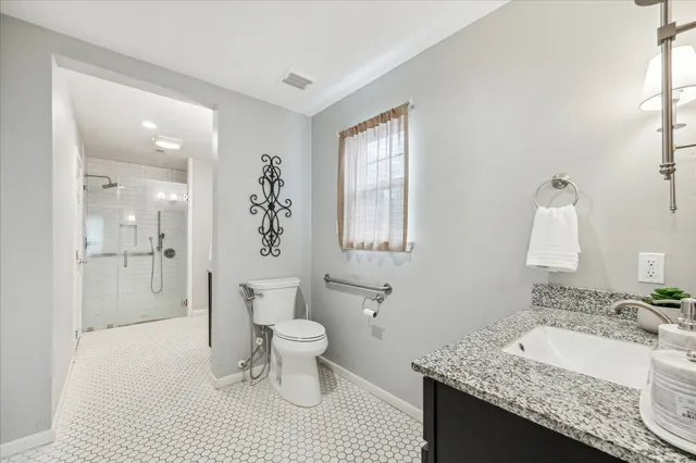 a bathroom with a granite countertop sink a toilet and shower