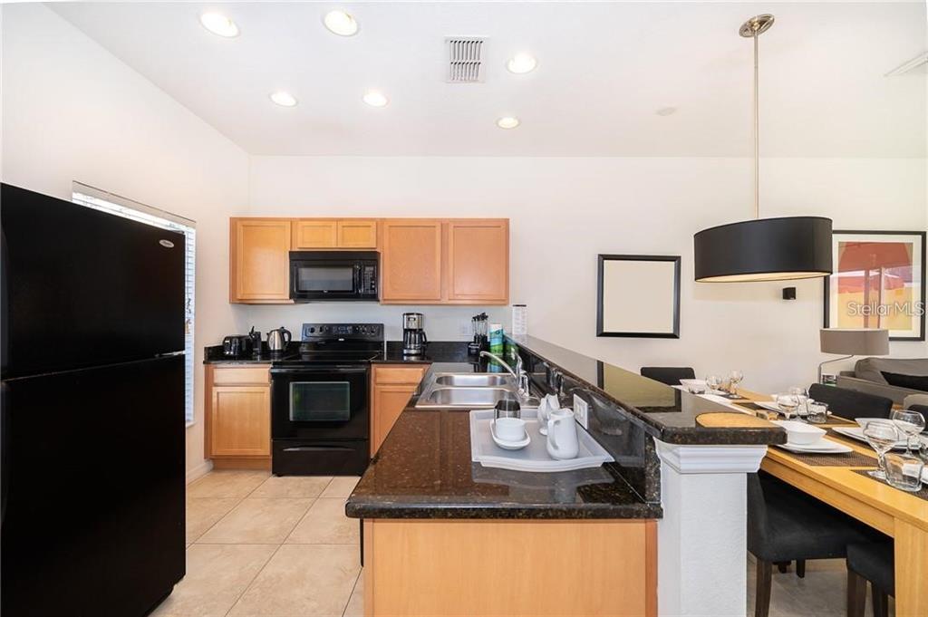 3007 White Orchid Road Kissimmee, FL 34747 - Photo 3 of 23 a kitchen with a refrigerator and a stove top oven