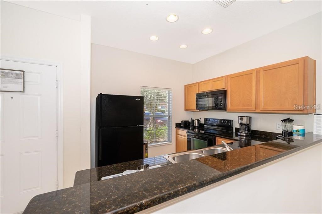 3007 White Orchid Road Kissimmee, FL 34747 - Photo 4 of 23 a kitchen with stainless steel appliances granite countertop a refrigerator and a sink