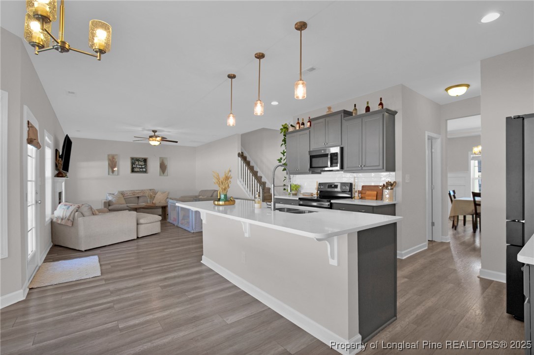 248 Rainy Beck Way Erwin, NC 28339 - Photo 14 of 44 a open kitchen view with stainless steel appliances kitchen island a stove a refrigerator a oven a dining table and chairs with wooden floor