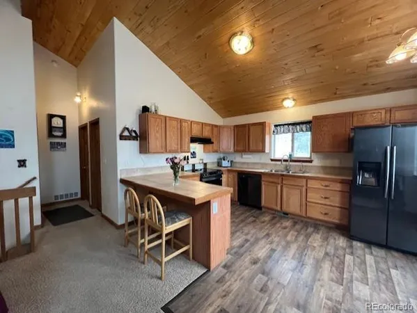 a kitchen with stainless steel appliances granite countertop a refrigerator a sink dishwasher a stove and white countertops with wooden floor