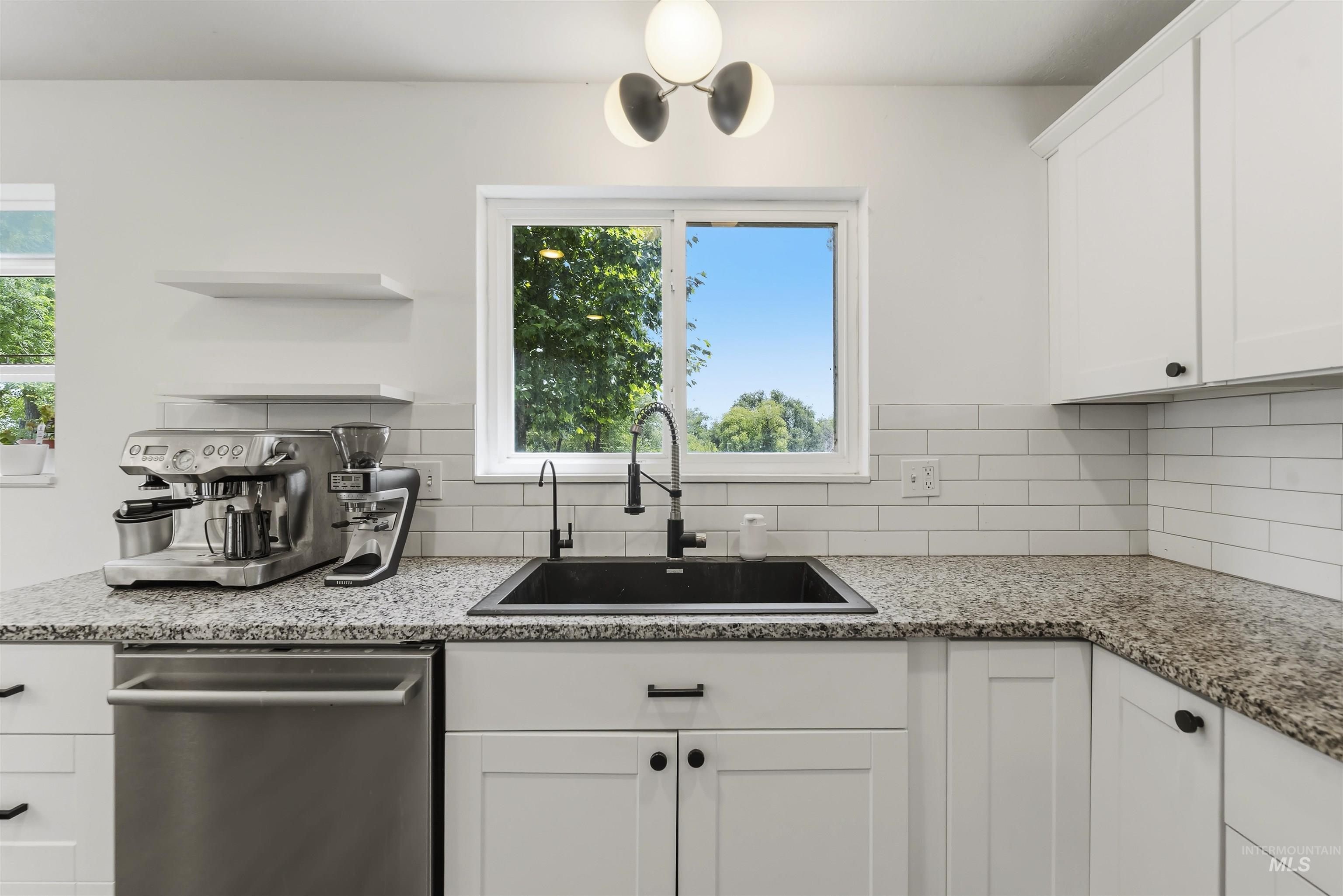 355 East Beacon Light Road Eagle, ID 83616 - Photo 13 of 47 Kitchen featuring white shaker cabinetry, speckled countertops, a black undermount sink with a matte black faucet, and white subway tile backsplash