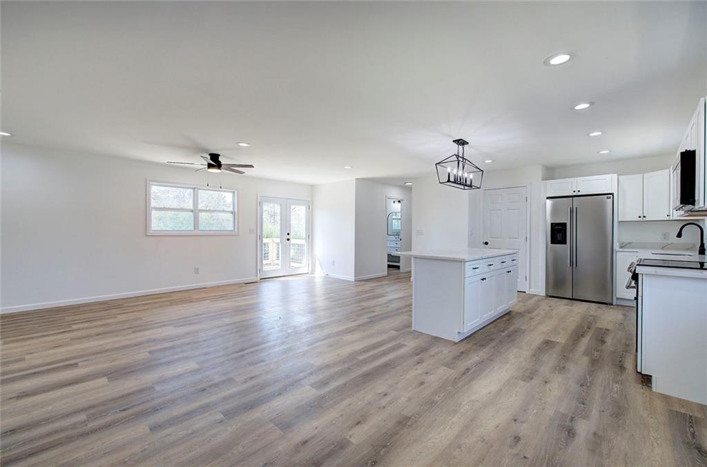 516 Baxter Road Southeast Calhoun, GA 30701 - Photo 9 of 47 an empty room with wooden floor and kitchen view