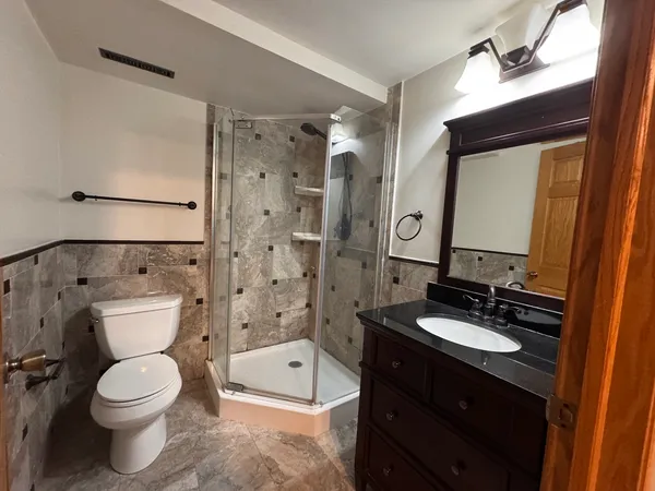 a bathroom with a double vanity sink toilet mirror and shower
