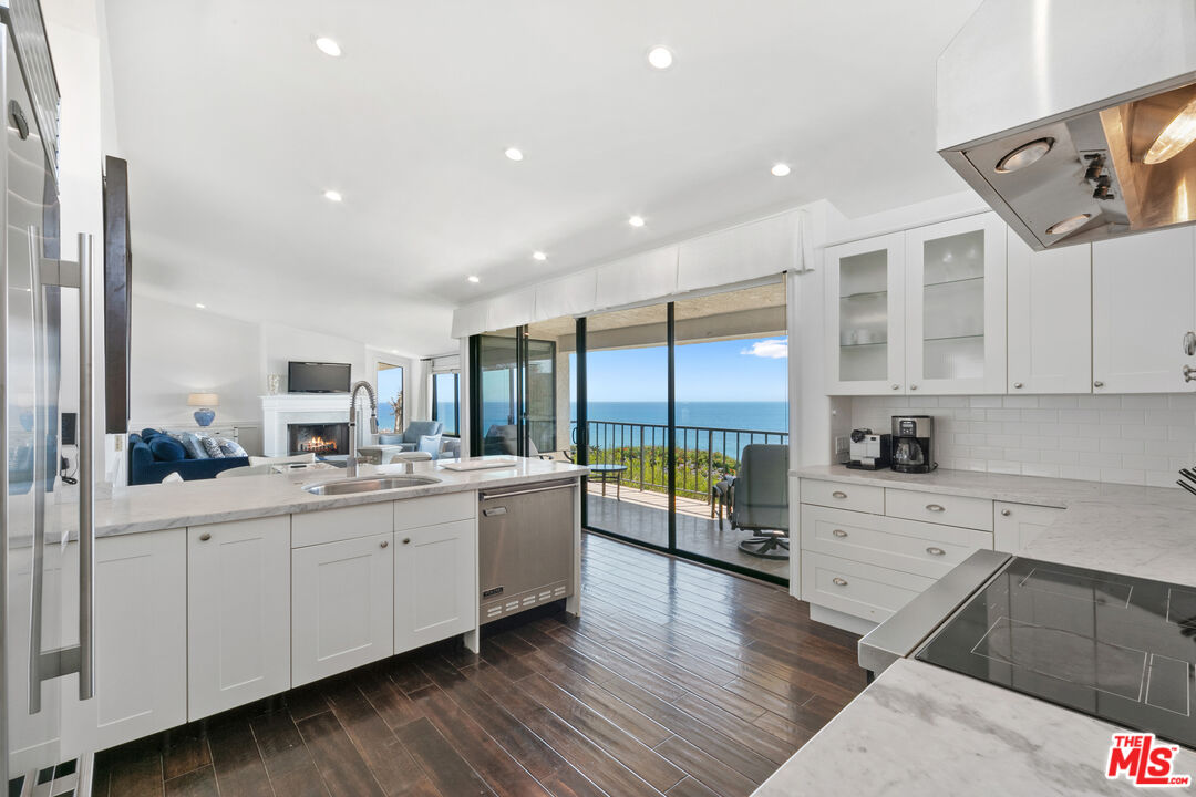 6801 Shearwater Lane Malibu, CA 90265 - Photo 12 of 33 a large kitchen with stainless steel appliances a large counter top a stove and a wooden floors