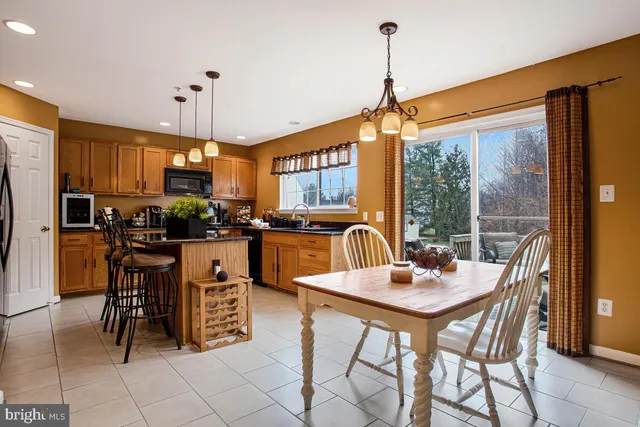 a kitchen with stainless steel appliances a dining table chairs a refrigerator with a dining table and chairs