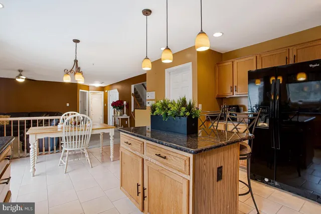 a kitchen with kitchen island granite countertop a stove a sink a dining table and chairs with wooden floor