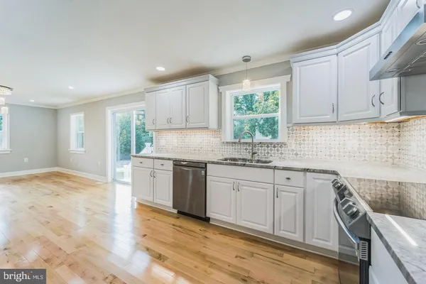 a kitchen with granite countertop a stove a sink and white cabinets