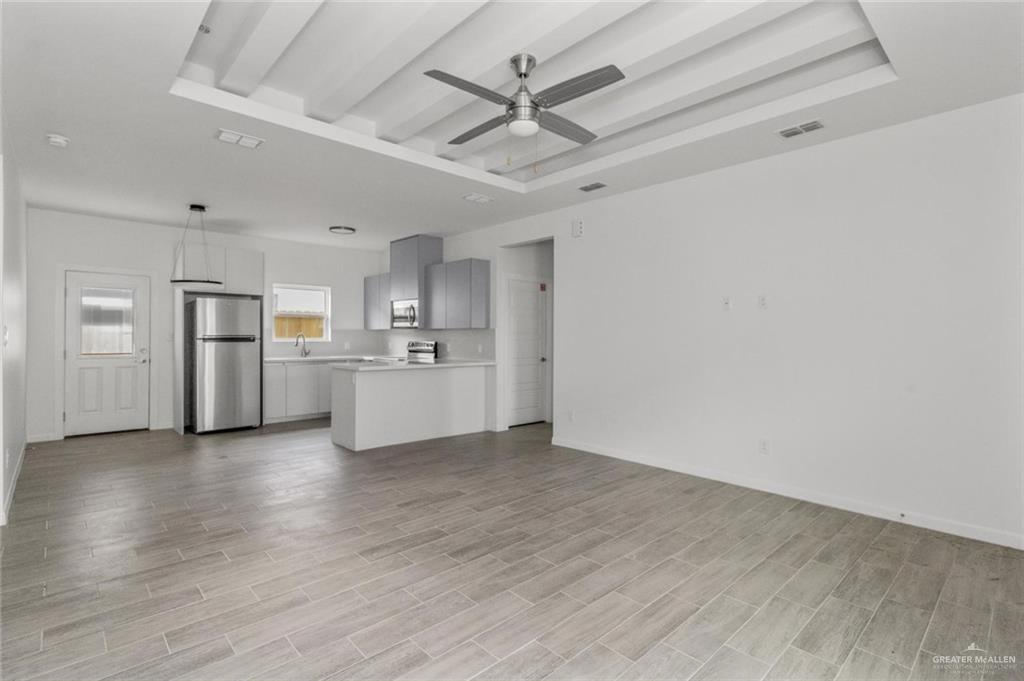 304 West Campeche Avenue, Unit 1 Alton, TX 78573 - Photo 3 of 11 Unfurnished living room with a tray ceiling, beam ceiling, a ceiling fan, and light wood-type flooring