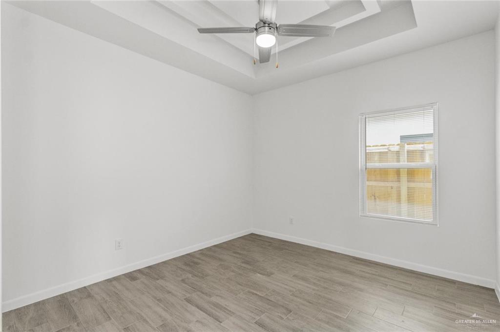 304 West Campeche Avenue, Unit 1 Alton, TX 78573 - Photo 4 of 11 Spare room with a tray ceiling, light wood finished floors, and a ceiling fan