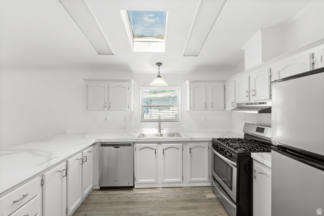 2600 North Hill Field Road, Unit 103A Layton, UT 84041 - Photo 9 of 31 Bright kitchen featuring a skylight, white cabinetry, integrated stainless steel appliances, marble-look countertops, and wood-finish flooring