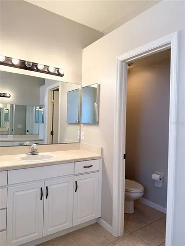 a spacious bathroom with a granite countertop sink a toilet and a mirror