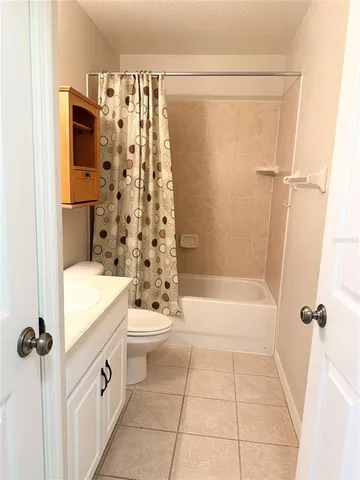 a bathroom with a granite countertop bathtub shower sink vanity and toilet