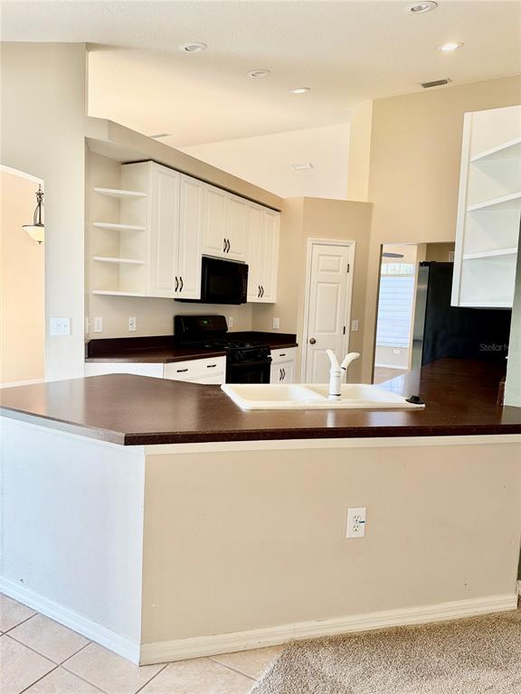 31224 Crestmont Court Wesley Chapel, FL 33543 - Photo 18 of 36 a living room with stainless steel appliances kitchen island a flat screen tv and a refrigerator