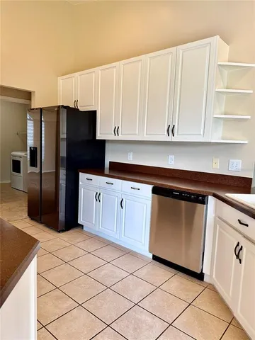 a kitchen with white cabinets and refrigerator