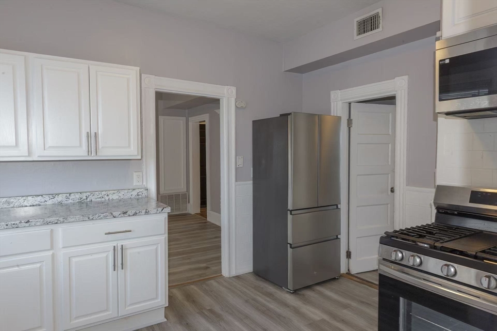 285 Medford Street, Unit 2 Somerville, MA 02143 - Photo 2 of 11 a kitchen with granite countertop a refrigerator and a stove top oven