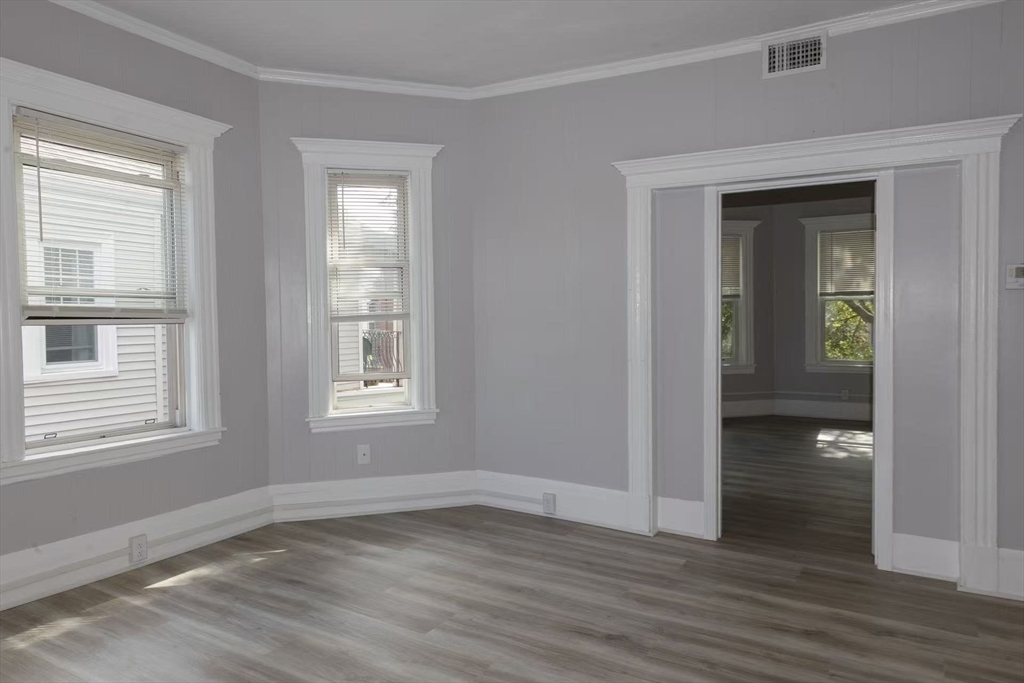285 Medford Street, Unit 2 Somerville, MA 02143 - Photo 4 of 11 a view of an empty room with wooden floor and a window