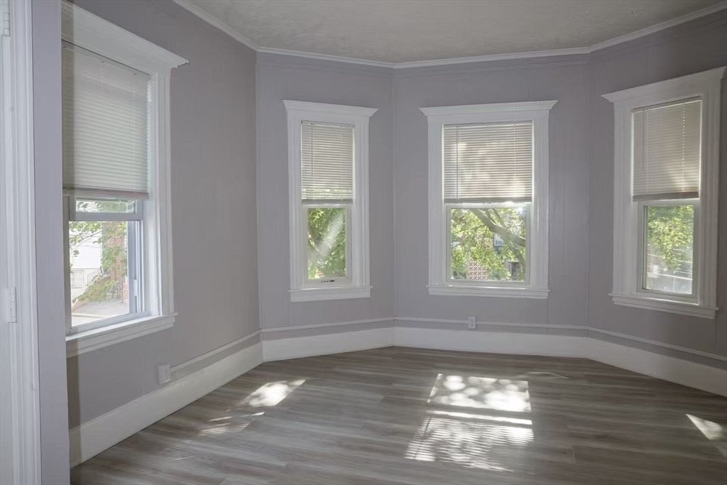 285 Medford Street, Unit 2 Somerville, MA 02143 - Photo 6 of 11 a view of an empty room with wooden floor and a window