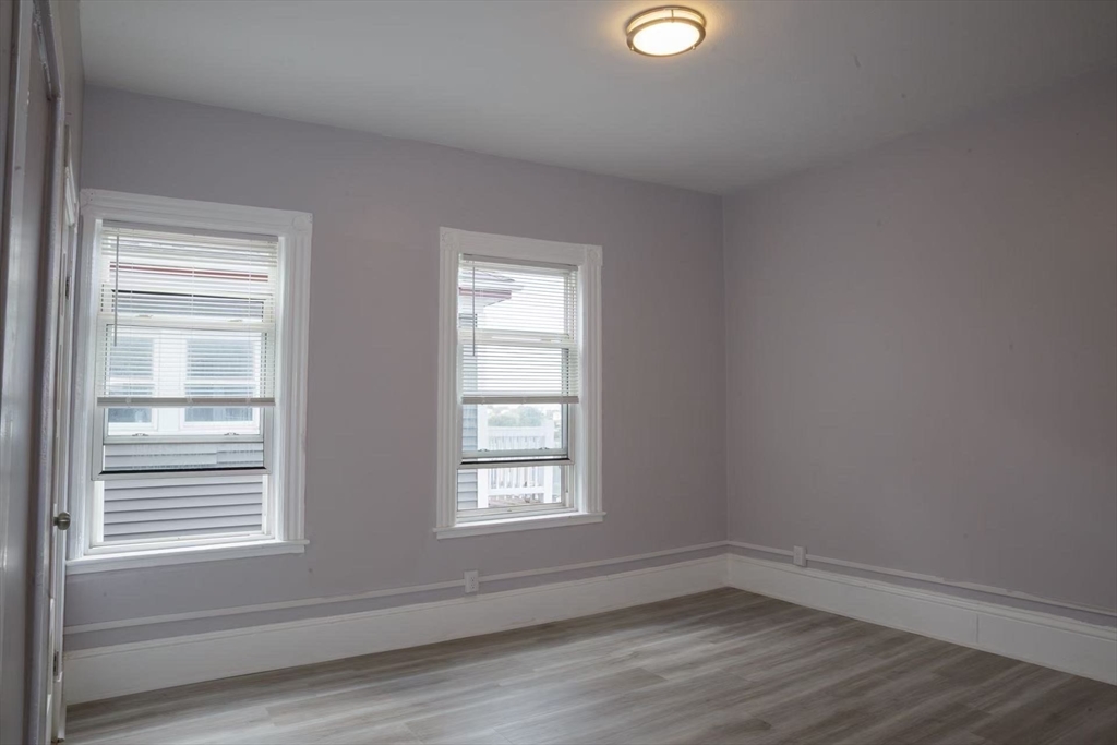 285 Medford Street, Unit 2 Somerville, MA 02143 - Photo 8 of 11 a view of an empty room with wooden floor and a window