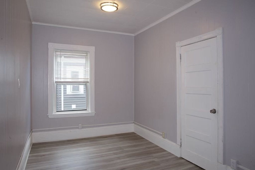285 Medford Street, Unit 2 Somerville, MA 02143 - Photo 9 of 11 an empty room with wooden floor and windows