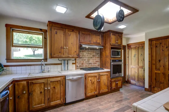 a kitchen with stainless steel appliances granite countertop a sink window and cabinets