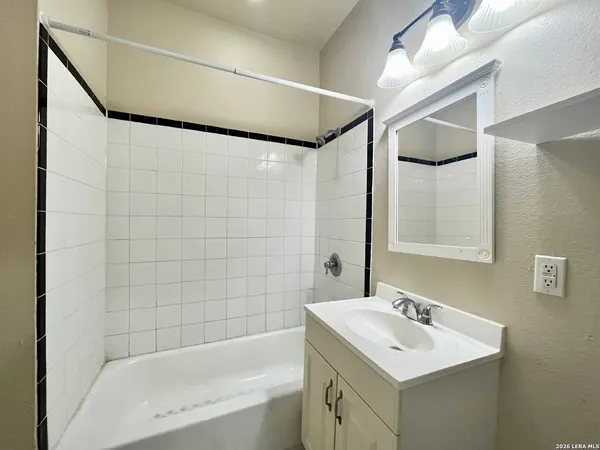 a bathroom with a sink mirror and a bathtub