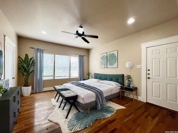 a spacious bedroom with a bed a table and wooden floor