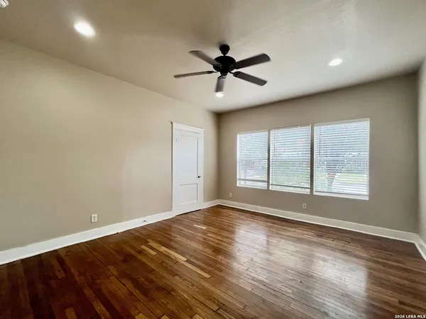 a view of empty room with wooden floor and fan