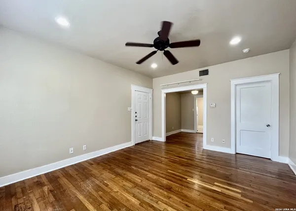 a view of empty room with wooden floor and ceiling fan