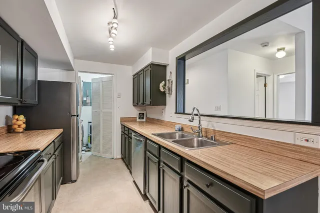 a living room with stainless steel appliances granite countertop a sink and a mirror