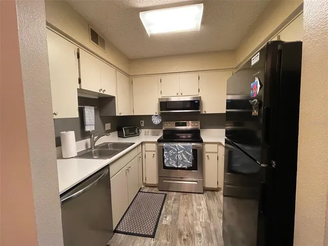 a kitchen with a sink a refrigerator and cabinets