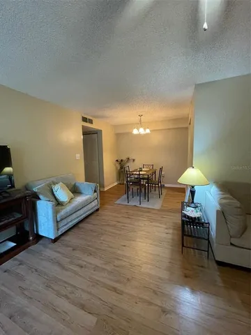 a living room with furniture and a dining table with wooden floor