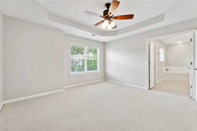 an empty room with a chandelier fan and windows