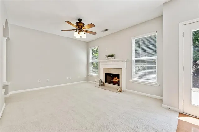 a view of livingroom with a fireplace a ceiling fan and windows