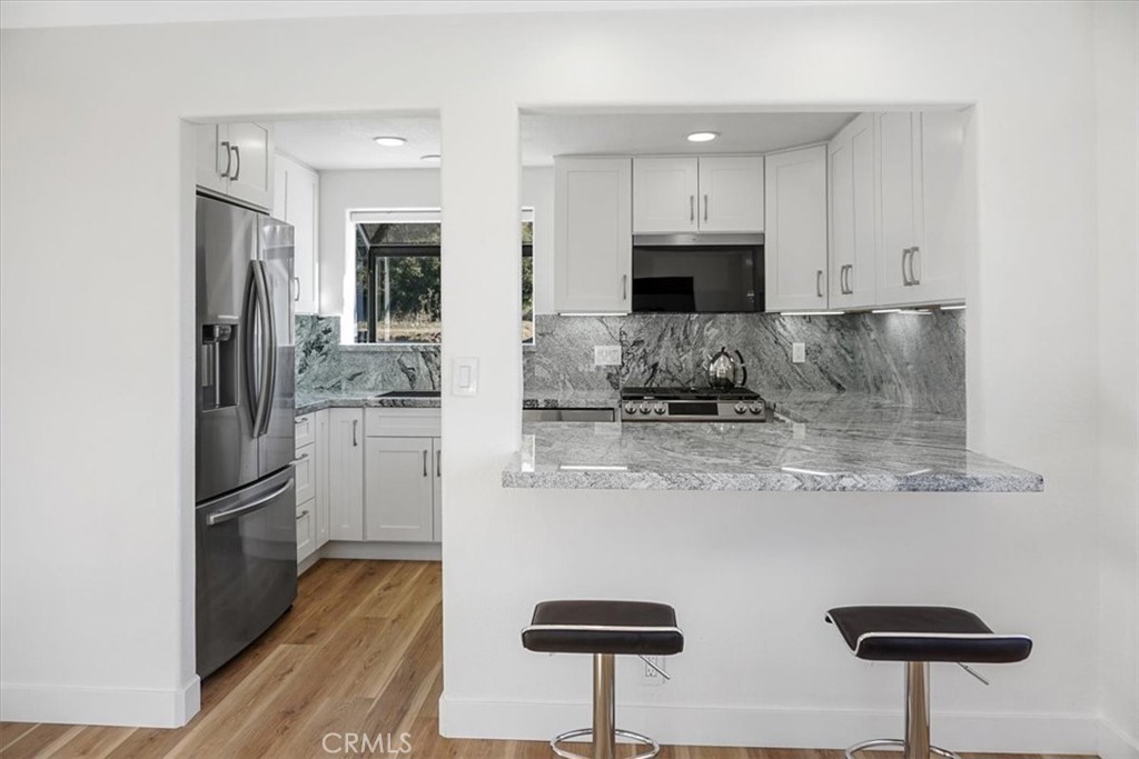 59470 Burnt Valley Road Anza, CA 92539 - Photo 6 of 18 a kitchen with stainless steel appliances granite countertop a refrigerator a stove a sink and white cabinets with wooden floor