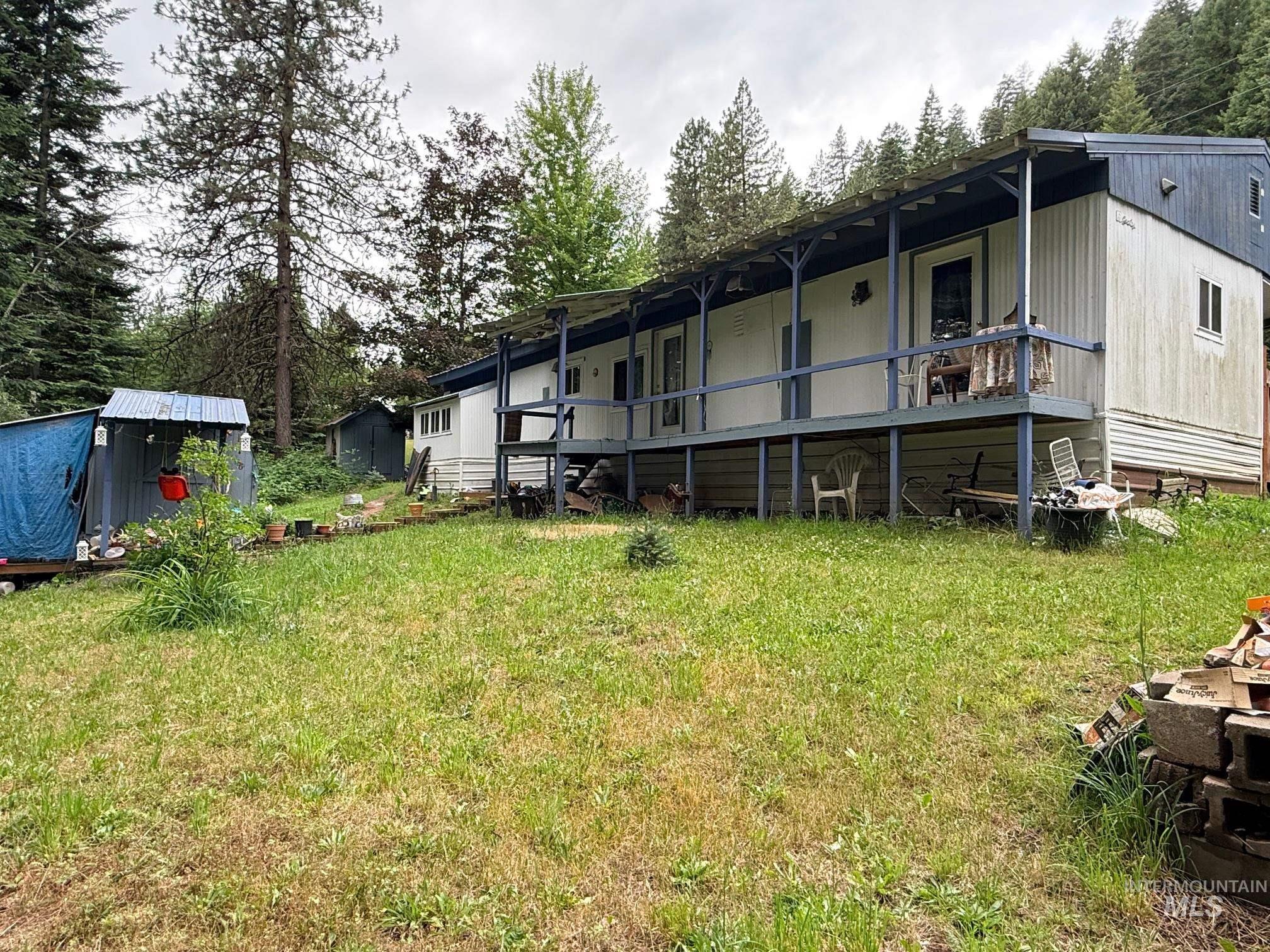 5742 Grangemont Road Orofino, ID 83544 - Photo 2 of 25 Exterior featuring a covered porch, wood railing, and a sloped lawn