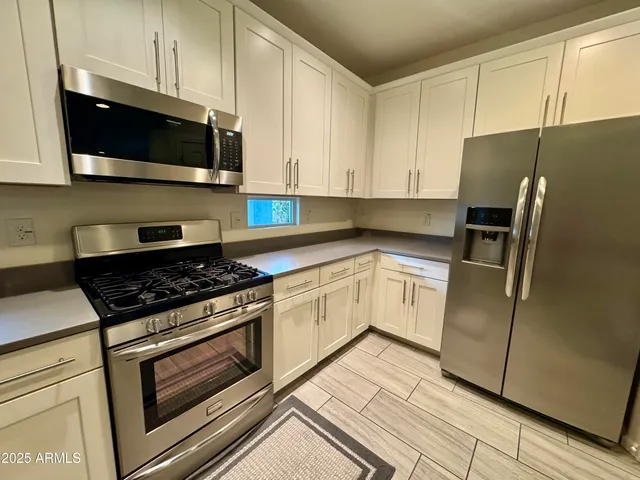 a kitchen with stainless steel appliances granite countertop a sink a stove a microwave a sink a refrigerator and cabinets