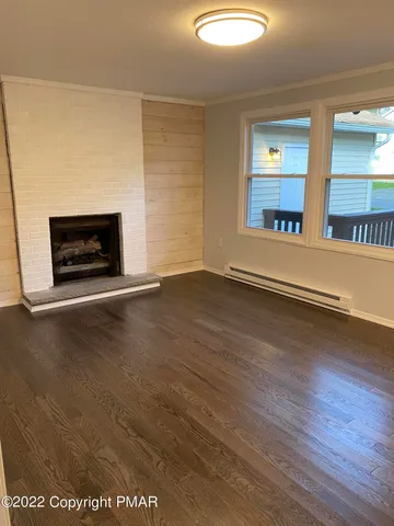 an empty room with wooden floor fire place and windows