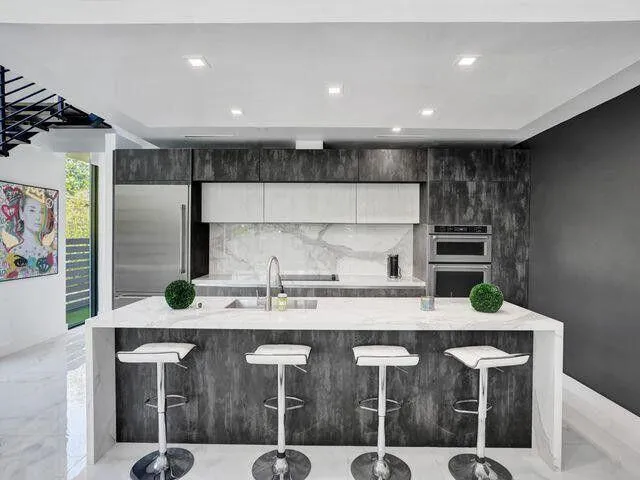 a kitchen with kitchen island granite countertop a sink a counter space and stainless steel appliances
