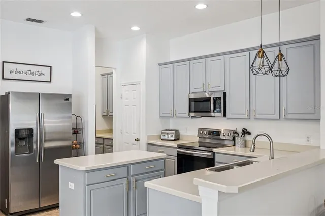 a kitchen with stainless steel appliances granite countertop a sink a stove a refrigerator and cabinets