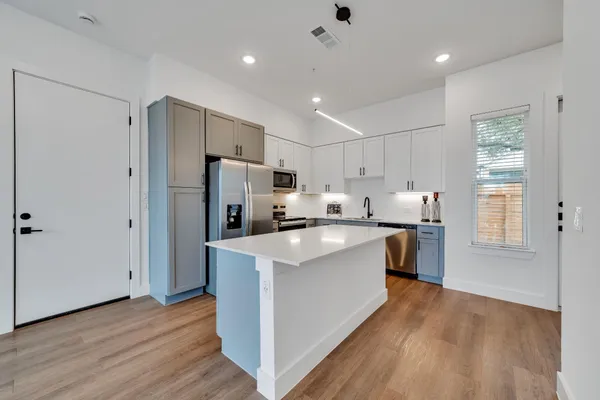 a kitchen with stainless steel appliances a refrigerator a stove top oven and wooden floors