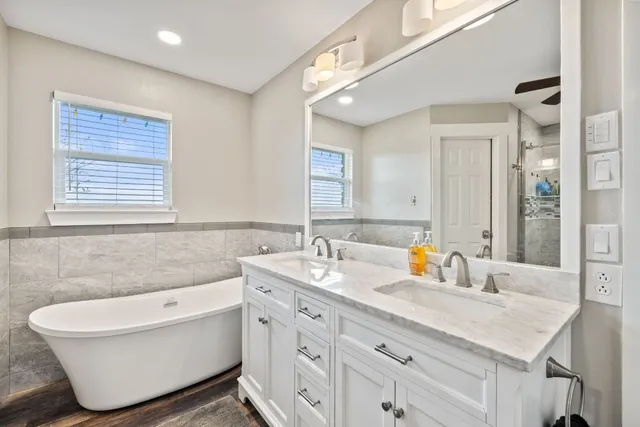 a bathroom with a sink double vanity granite tub and mirror