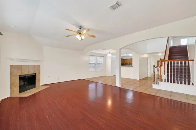 a view of an empty room with wooden floor fireplace and a window