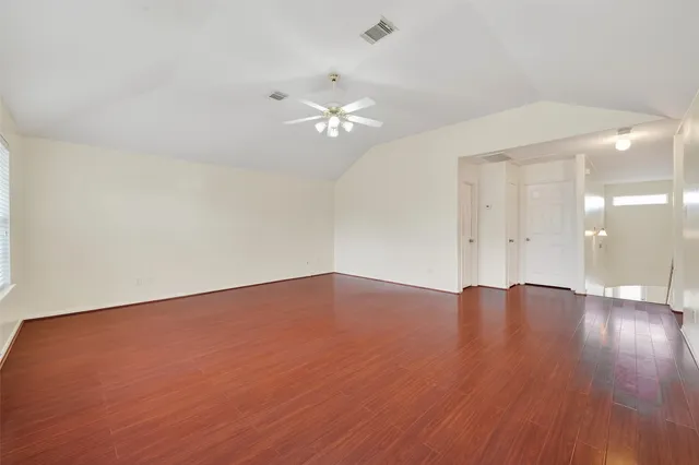 an empty room with wooden floor and fan