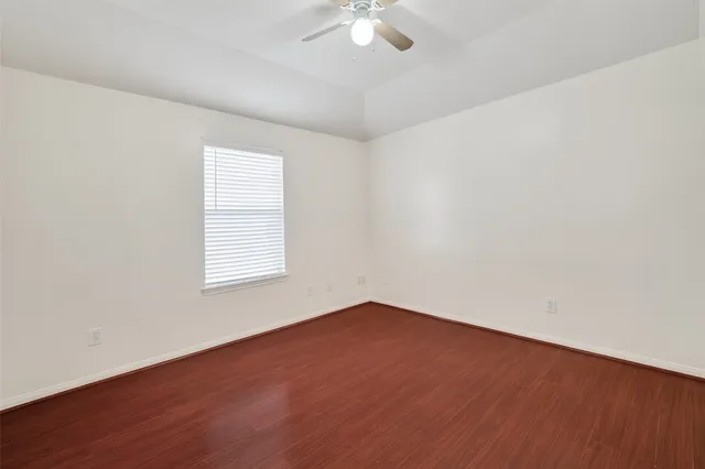 an empty room with a chandelier fan and windows