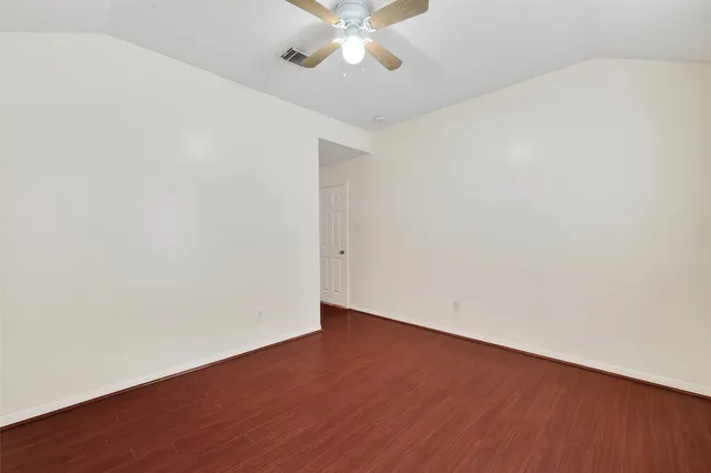an empty room with wooden floor and fan