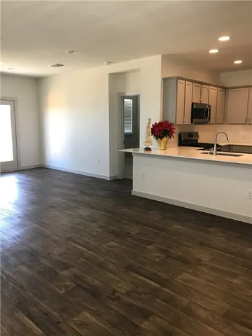 a view of kitchen with stainless steel appliances granite countertop a sink wooden floor and a window